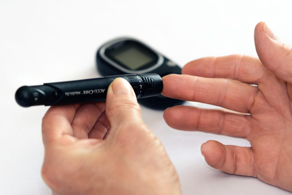 Person using a blood glucose meter and lancing device to check blood sugar levels for diabetes management.