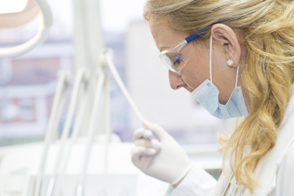 Healthcare professional wearing protective equipment while providing medical care during a patient examination.