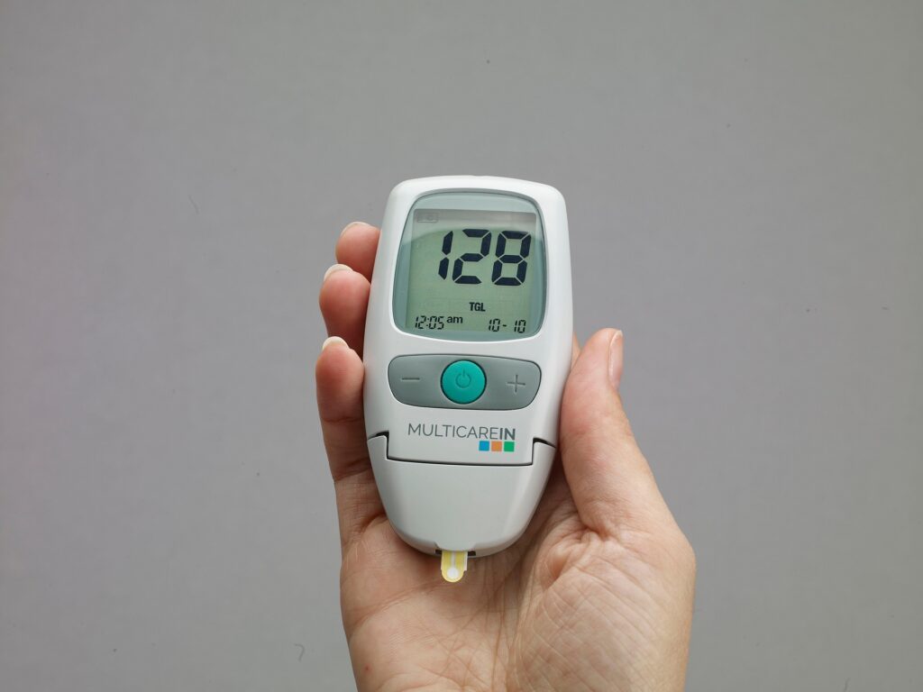 Person holding a blood glucose meter displaying a blood sugar reading during a diabetes self-monitoring test.