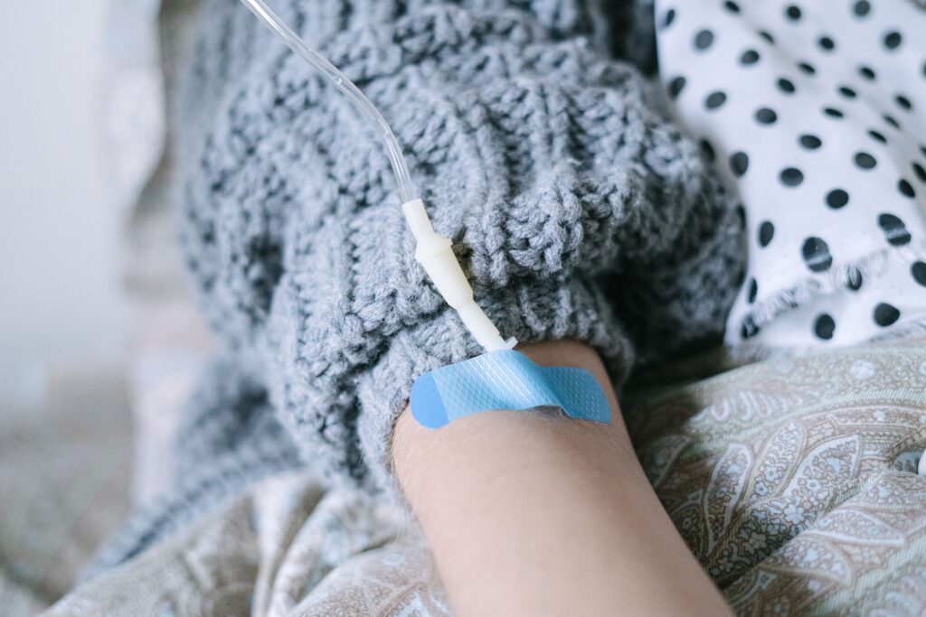 Close-up of an intravenous (IV) line delivering fluids or medication to a patient in a healthcare setting.