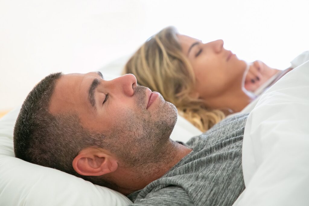 Adult couple sleeping peacefully in bed, illustrating healthy sleep habits and restorative rest