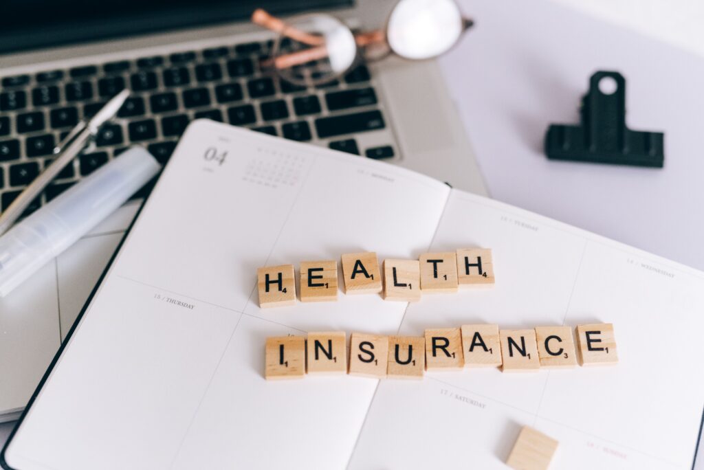 Planner with the words "Health Insurance" arranged on letter tiles, representing healthcare coverage and insurance planning.