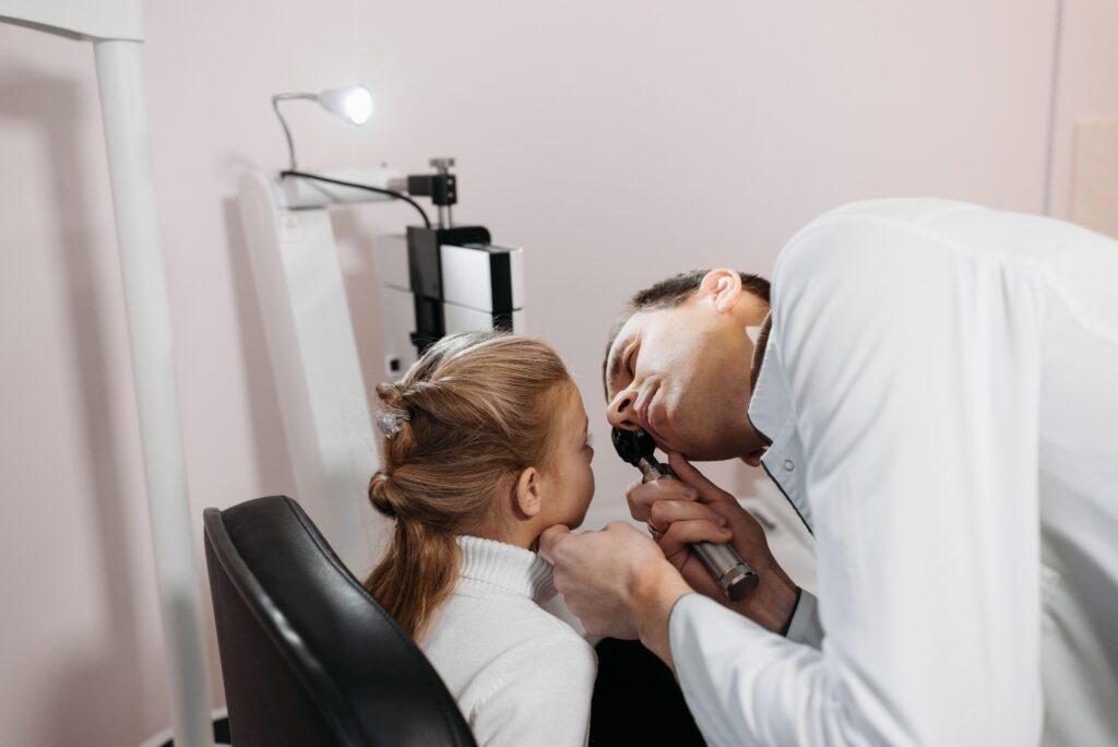 Doctor performing a routine ear examination on a child during a pediatric wellness visit.