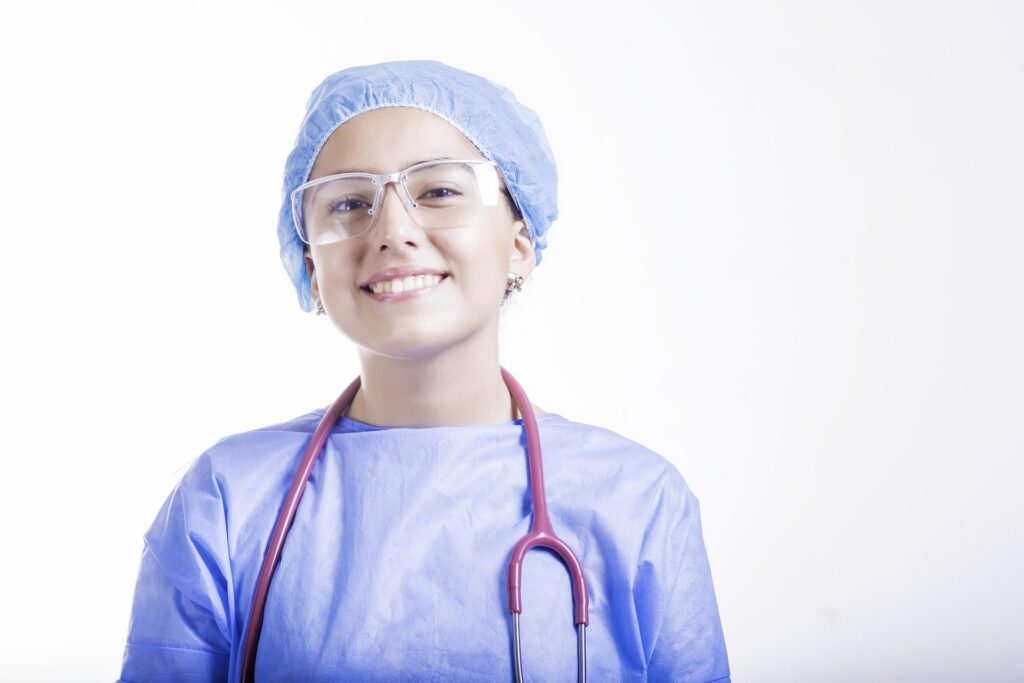 Smiling pediatric healthcare professional wearing protective medical attire and a stethoscope.