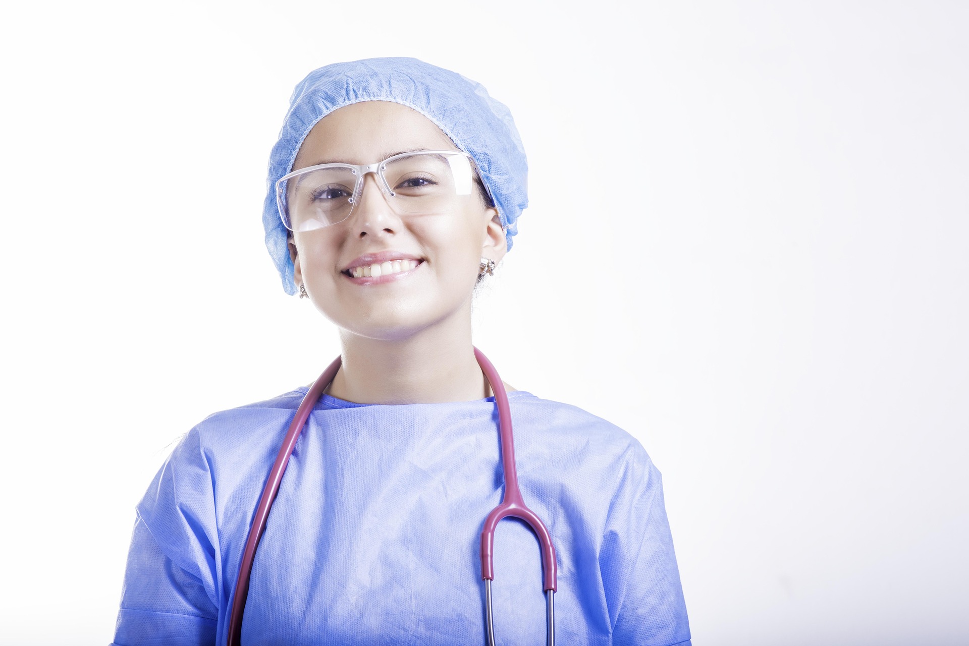 Smiling pediatric healthcare professional wearing protective medical attire and a stethoscope.